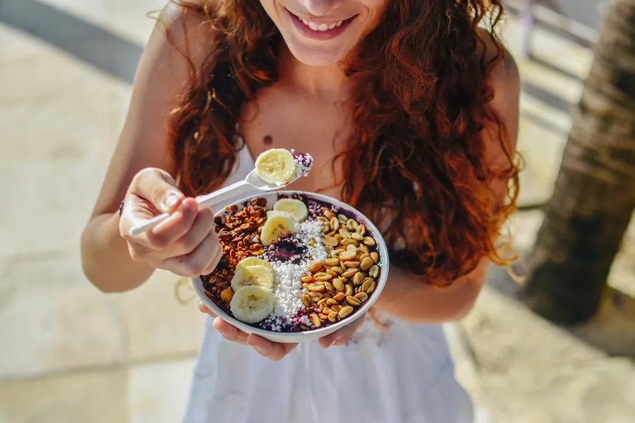 Young girl eating Acai bowl on street